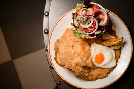 top view on plate with chop with roasted egg and potato and salad on the tableの写真素材