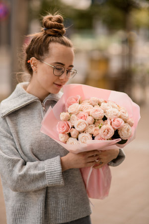 charming view of handsome woman with luxury bouquet of pink roses in wrapping paper in the handの写真素材