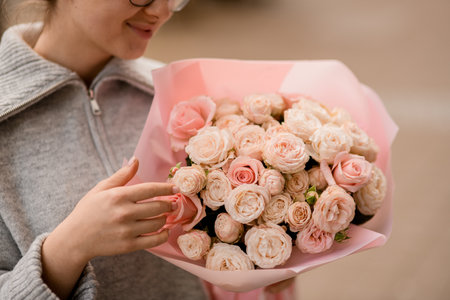selective focus on lush bouquet of roses in wrapping paper in the hands of young pretty womanの写真素材