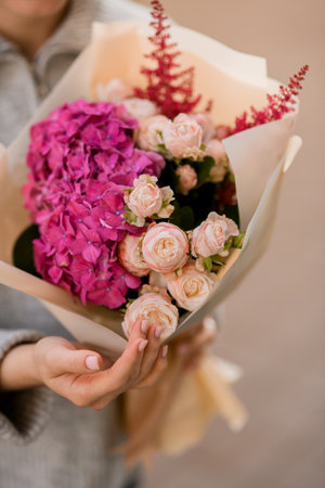 Close-up of lush bouquet of of pink roses and hydrangea and heather in female handの写真素材