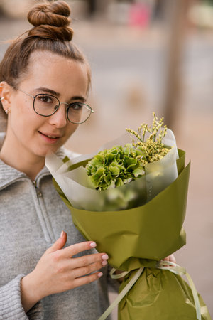 young woman with beautiful flower bouquet of green hydrangea and gypsophila in wrapping paperの写真素材