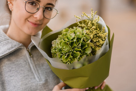 Cropped photo of woman with beautiful flower bouquet of green hydrangea and gypsophila in wrapping paperの写真素材