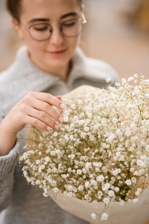 Close-up view on bouquet of white gypsophila flowers in hands of womanの写真素材