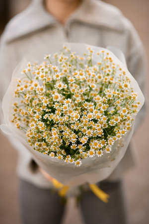 selective focus on white small camomile flowers in bouquet in wrapping paperの写真素材