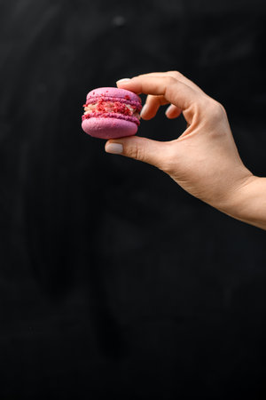 side view of female hand holding delicious sweet pink macaronの写真素材