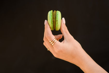 close-up of female hand gently holds delicious sweet green macaronの写真素材