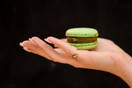 close-up of female hand holds on the palm delicious sweet green macaronの写真素材