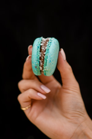 close-up of female hand holds delicious sweet turquoise macaronの写真素材