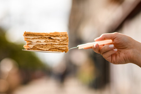 Great close-up view of slice of sweet honey cake on a metal cake spatula in hand
