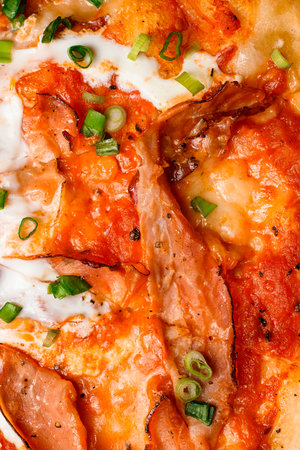 Detailed photo of appetizing hot pizza with prosciutto, egg and green onionの写真素材