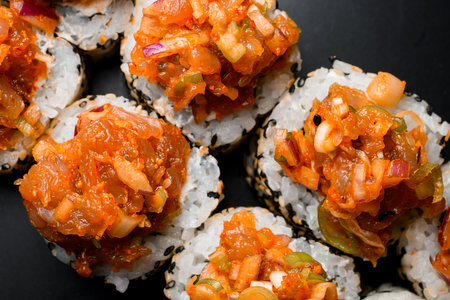 Freshly made appetizing asian roll with sesame, caramelized onions and raw fish on black backgroundの写真素材