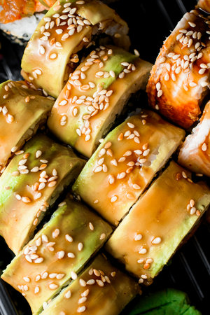 Top view on sushi set with eel, avocado, teriyaki sause, fresh vegetables and sesameの写真素材