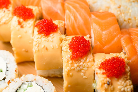 Appetizing set of rolls with cheese, salmon, tobiko calve, white sesame, Philadelphia cheese on wooden serving board.の写真素材