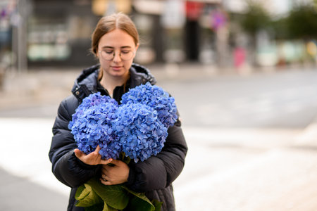 Girl florist gently holding large bouquet of fresh hydrangea flowers in blue colors