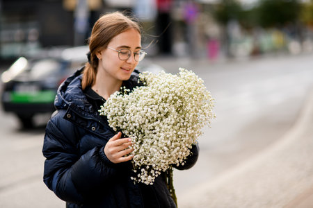 Brunette woman with long hair holding stylish large bouquet of white gypsophilaの写真素材