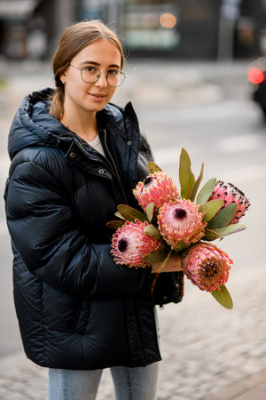 Beautiful girl holding in hands fresh bouquet of pink Protea artichoke flowersの写真素材