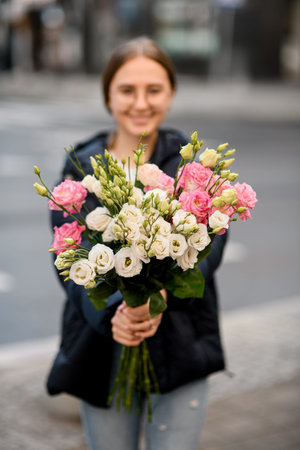 Young woman holding fresh colorful bouquet of eustoma flowers in handsの写真素材