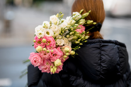 Gorgeous bouquet of fresh eustoma flowers in cream, pink and yellow colors on woman florists shoulderの写真素材