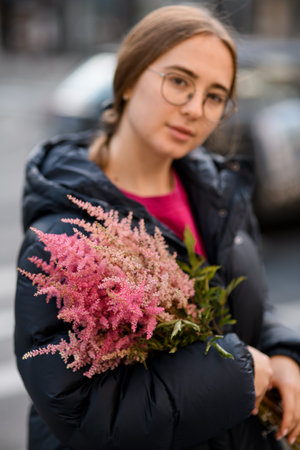 Smiling young woman holds colorsful branches of wildflowers in her hands on blurred backgroundの写真素材