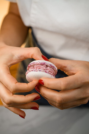 Close up view of girl confectioners hands connecting two shells of macaronsの写真素材