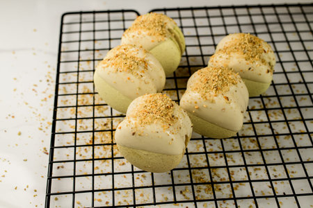 Side view of fresh delicious pistachio macarons decorated with white chocolate and chopped peanuts
