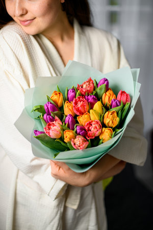 Young lady hold bouquet of tulips, looks at empty space, enjoy beautiful floversの写真素材