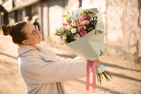 Woman florist rises up bouquet of fresh eustoma flowers in cream and pink colorsの写真素材