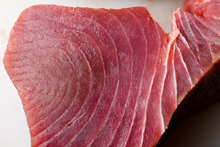 Delicious huge raw yellowfin tuna fish steak on white cutting counter, macro shotの写真素材