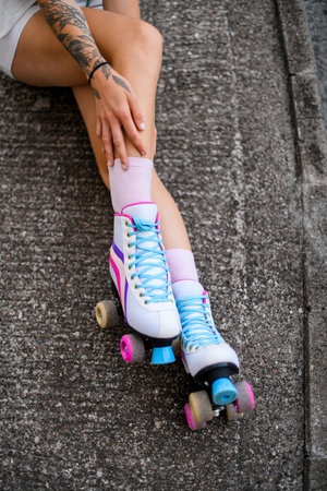 Female legs in colorful vintage roller skates shoes isolated on gray asphalt background
