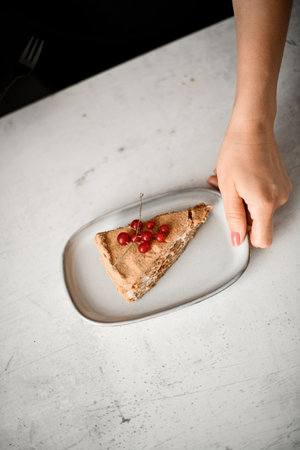 Female hand holds plate with classic french dessert Napoleon decorated with red currant. top view