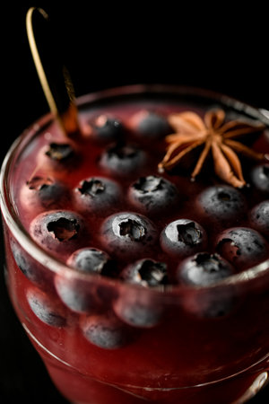 Macro shot of tasty red cocktail with blueberries and allspice in old fashioned drinking glass.. Table top view, dark backgroundの写真素材