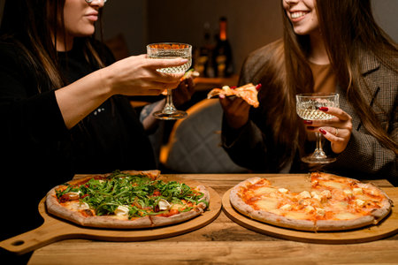 A flavorful duet. Girls relishing pizza and wine together.の写真素材