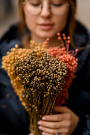 Young pretty brown-haired girl stands on a city street with a bouquetの写真素材