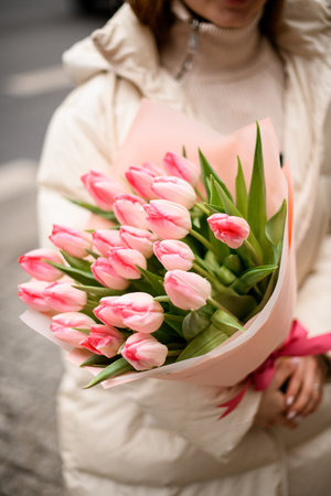 Large bouquet of pink tulips in a pink wrapper is held by a womanの写真素材