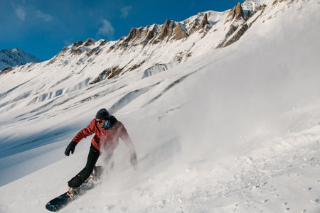 Snowboarder maneuvers down the slope on his snowboardの写真素材