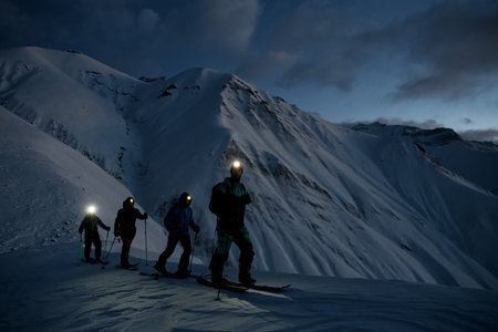 Four silhouettes of skiers moving down a snowy slope against the background of a mountain landscapeの写真素材