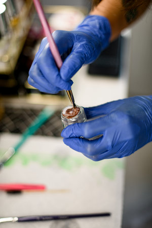 Female hands mixing dye in a glass cup for mixing eyebrow paintの写真素材