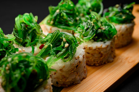 Portion of sushi rolls with a pile of green algae, close upの写真素材