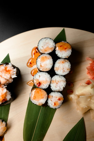 Top view of part of a set of sushi rolls filled with shrimp meat filled with sauce, on banana leavesの写真素材