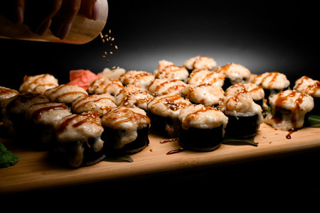 Side view of a large set of baked sushi rolls with unagi sauce sprinkled with sesame seedsの写真素材