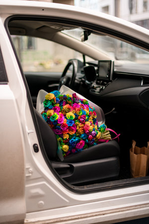 Huge bouquet of multi-colored roses lies on the front seat of a carの写真素材