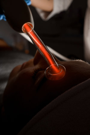 Top view of an electric cosmetology device darsonval, which a beautician applies to a womans face