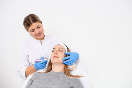 Female hands of a beautician perform the RF lifting procedure in a beauty salonの写真素材