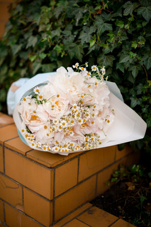 Beautiful bouquet of peonies and daisies lies on a ceramic tile borderの写真素材