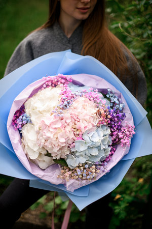 Close-up photo of a huge bouquet of hydrangea with hypophylla in a blue and pink wrapper
