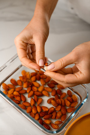 Female hands hold an almond nut and peel it