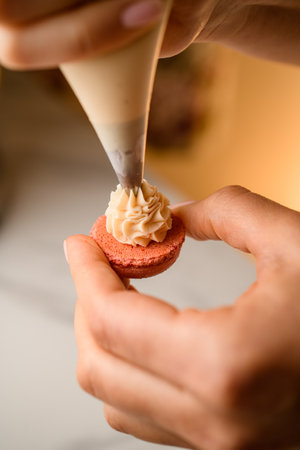 Confectioners hands apply cream to the macaroon blankの写真素材