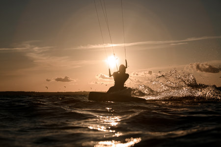 Female wakeboarder rides a wakeboard, holding on to a handle on three cableの写真素材