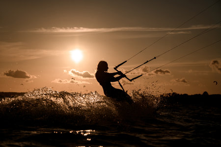 Female wakeboarder rides a wakeboard, holding on to a handle on a cable, side viewの写真素材