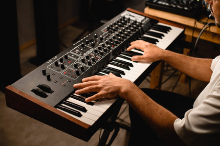 In a recording studio, a musician plays a modern synthesizer